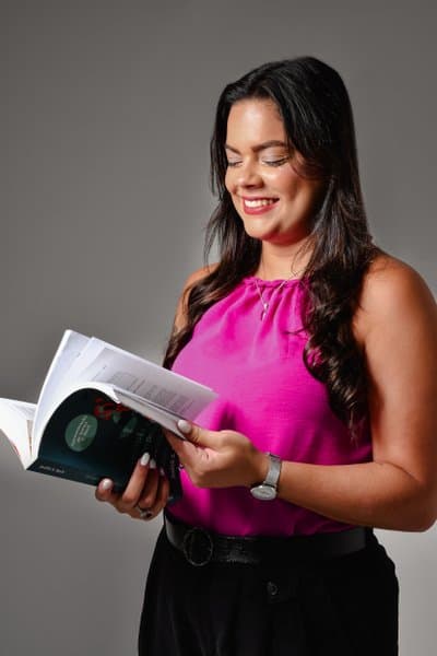 Rebecca Ramos sorrindo enquanto lê um livro